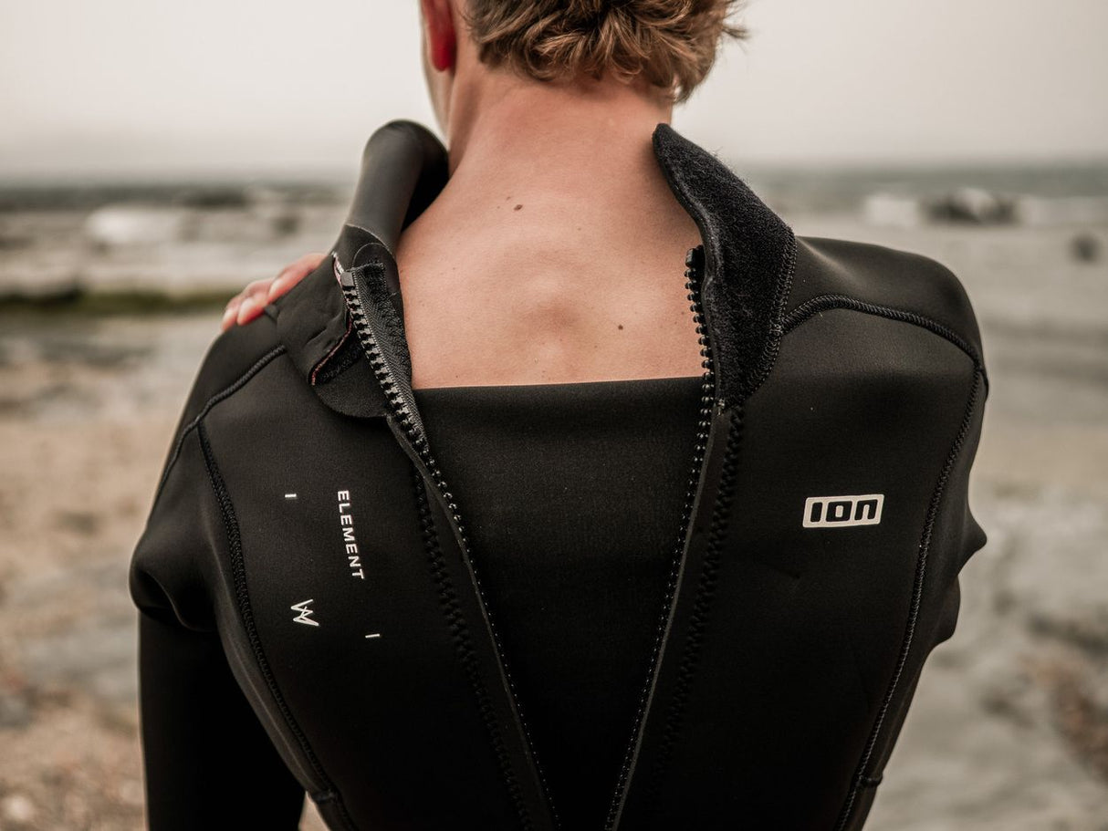 ION Element 5/4 Back Zip Neoprenanzug in Schwarz, Rückenansicht mit Rückenverschluss, am Strand