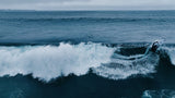 ION Seek Amp 6/5 Neoprenanzug mit Kapuze in Blau, Frontalansicht im Wasser beim Surfen