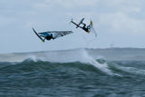 ION Axxis Windsurf Trapez Herren 2026 in Blau, Athlet in Aktion über Wellen, Seitenansicht