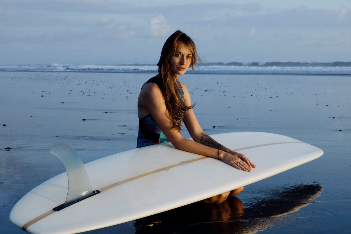 ION Amaze V-Back 1.5 Damen Neoprenanzug in Schwarz, Frontansicht mit Surfboard am Strand