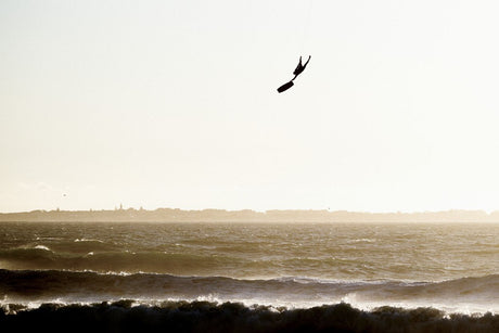 ION Nova Kite Trapez Damen 2024 in Schwarz, Kitesurfer in Aktion über Wellen, Frontalansicht