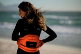 ION Muse Kite Trapez 2026 orange Kiteboard-Trapez mit schwarzen Details, von vorne getragen am Strand