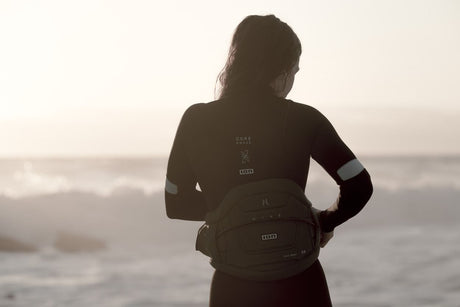 ION Muse Kite Trapez 2026 schwarzes Trapez, getragen von Person am Strand mit Meereshintergrund, Frontalansicht