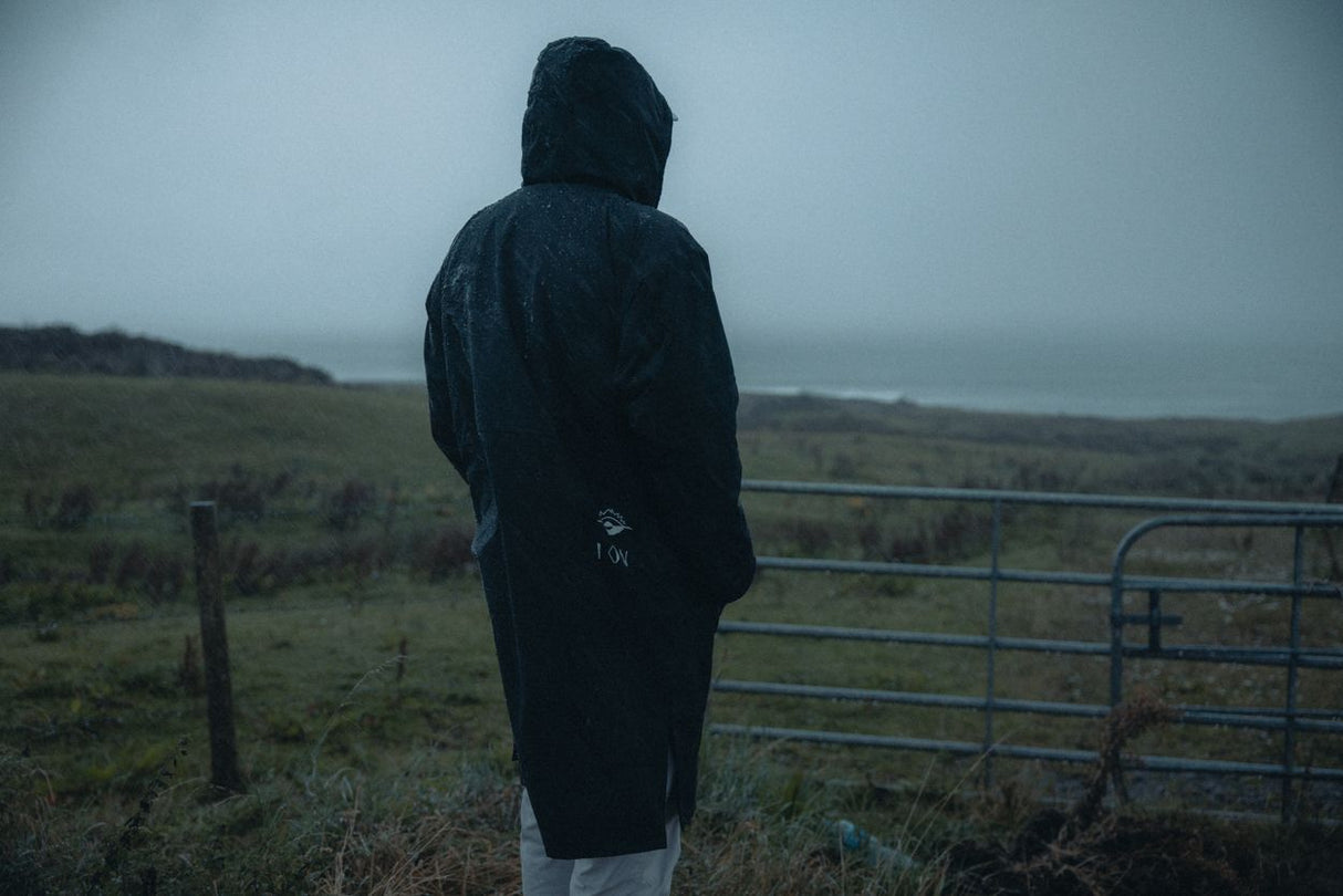 ION Storm Coat Unisex 2026 in Schwarz, wasserabweisend, Rückansicht auf Person in Landschaft
