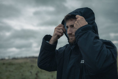 ION Storm Coat unisex 2026 dunkelblau, Funktionsjacke mit Kapuze, getragen von Person in Außenszenerie