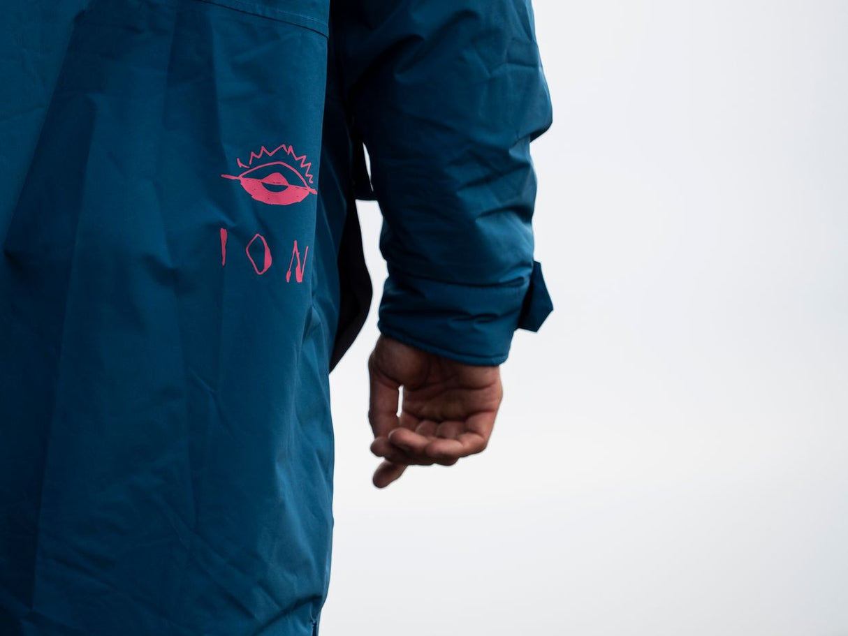 ION Storm Coat unisex 2026 in Dunkelblau mit pinkem Logo, Seitenansicht, Detailaufnahme Ärmel und Schulter