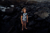 ION Rashguard Capture 2026 in Schwarz mit Muster, Kurzarm, getragen an Felsen am Strand