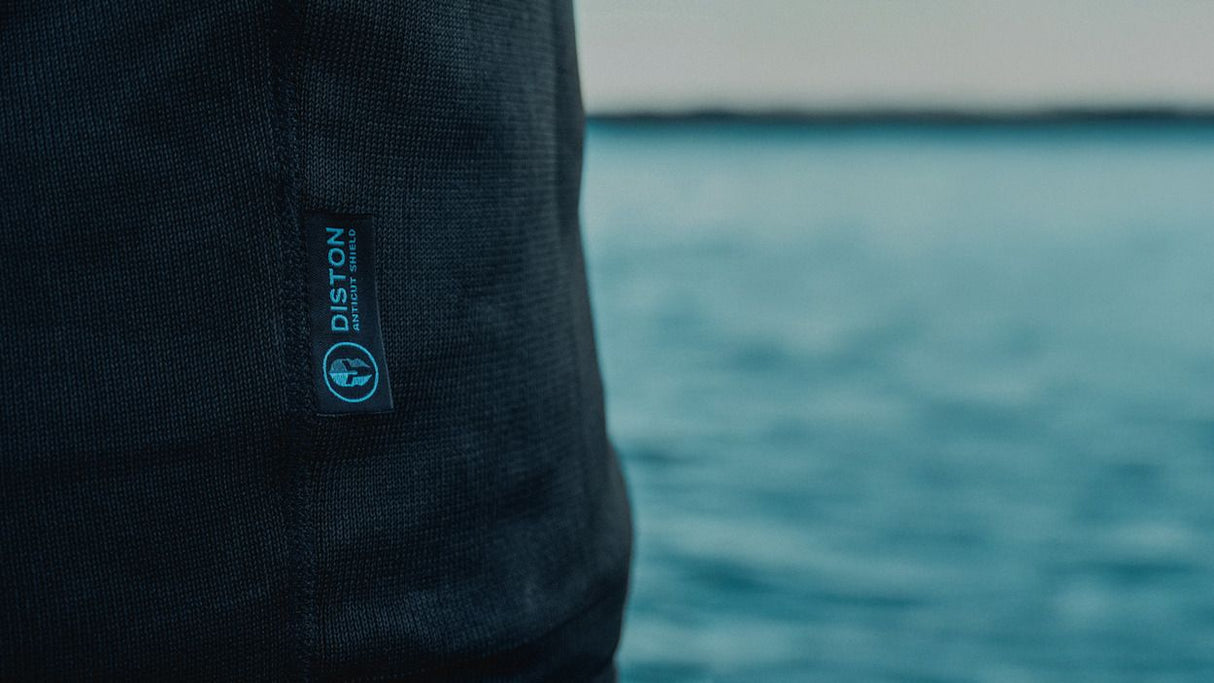 ION Rashguard LS Surf Shield SS2026, dunkelblau, Langarm-Neopren Oberteil, Detail mit Logo, Nahaufnahme vor Meer