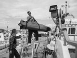 ION Kite Gearbag Core 2026 schwarz, Mann trägt aufgerollte Tasche auf Bootsanleger, Wassersportzubehör