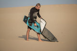 ION Twintip Boardbag Core 2024 grau, Mann mit Kiteboard und Boardbag am Strand, Schutzcase