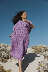 ION Surf Poncho Select Reefside 2024 in Violett mit geometrischem Muster, getragen am Strand