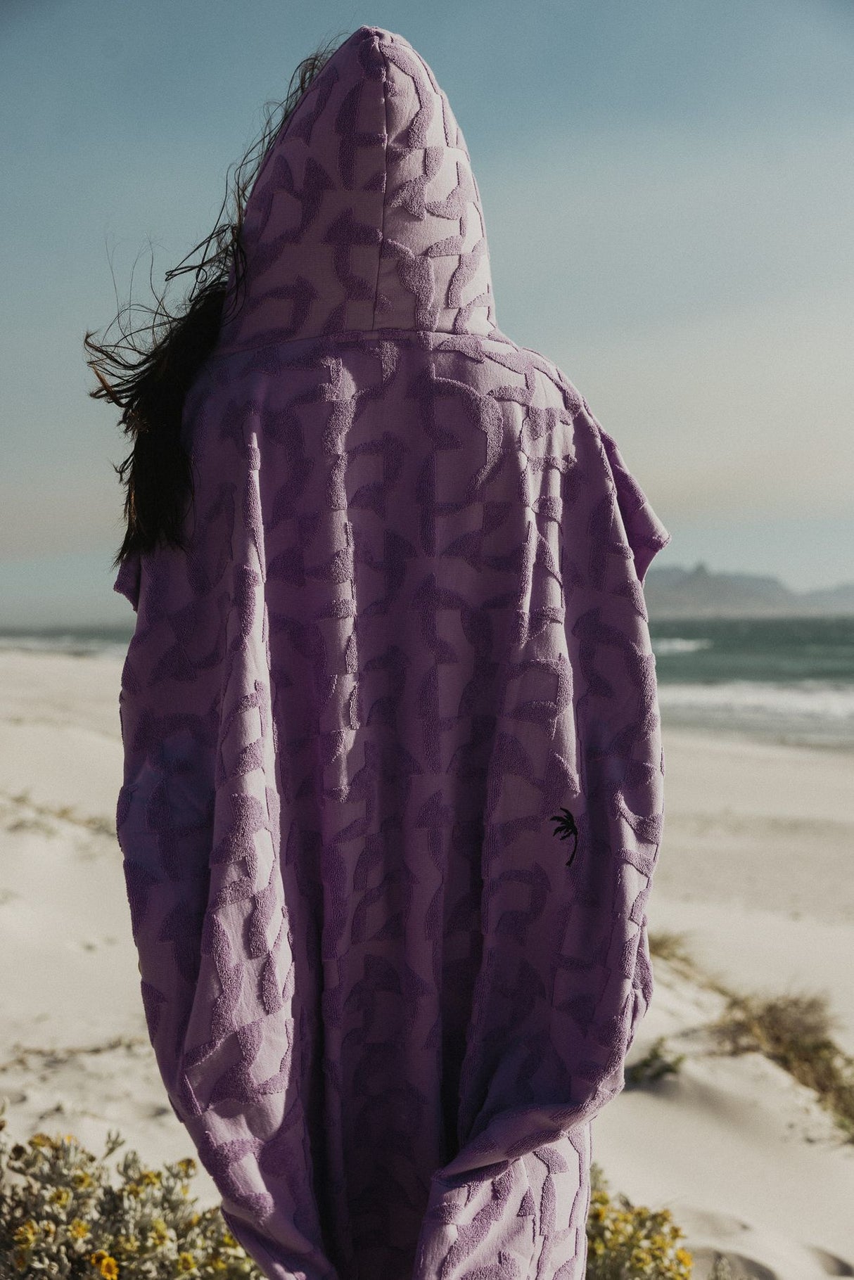 ION Surf Poncho Select Reefside 2024 in Violett, Rückansicht am Strand getragen