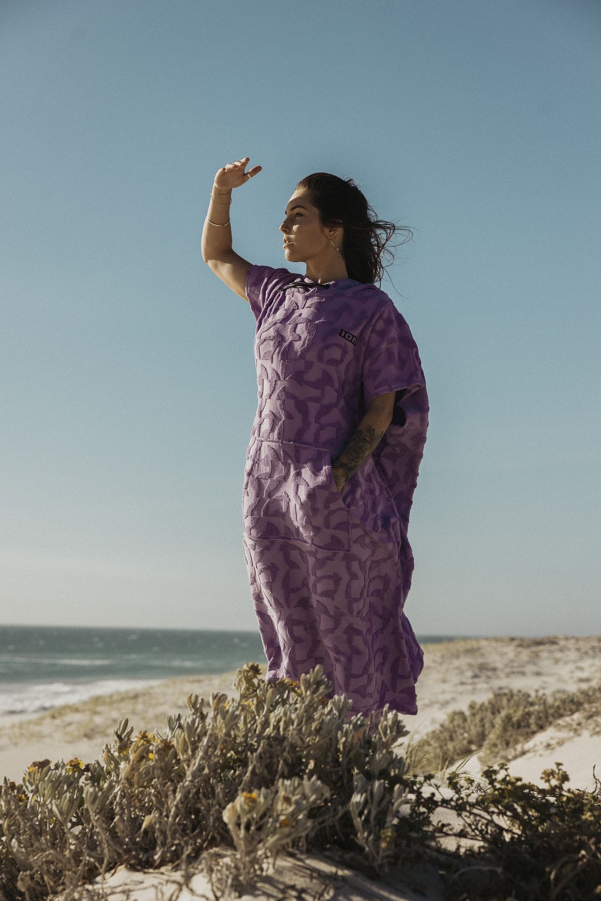 ION Surf Poncho Select Reefside 2024 in Violett mit Muster, getragen am Strand, Seitenansicht