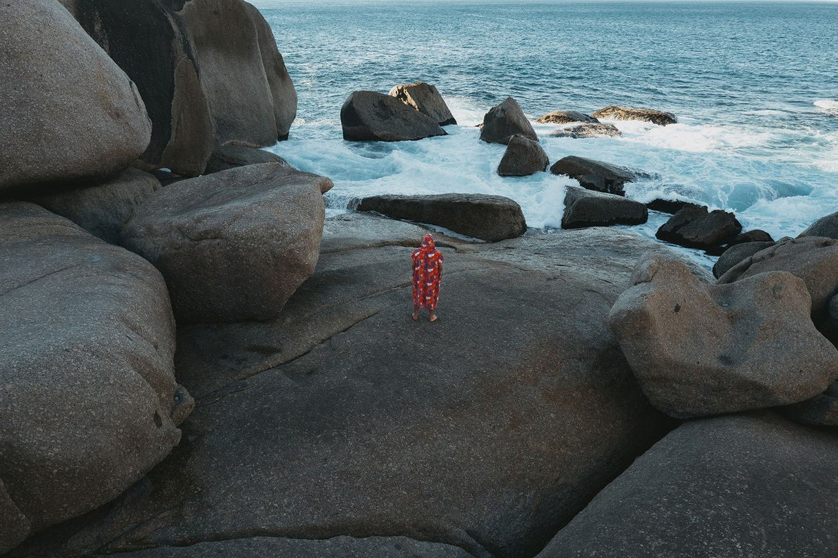 ION Poncho Core Lumen 2026 in Rot, Funktionsponcho am Strand getragen, Frontalansicht