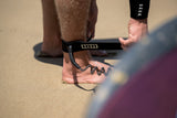 ION Wing Board Leash Core Coiled Ankle schwarz, Spiralkabel, am Fuß getragen am Strand