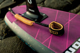 ION Wing Board Leash Core Coiled Knee schwarz-gold, aufgerollt auf pink-weißem Board, Draufsicht