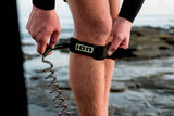 ION Wing Board Leash Core Coiled Knee, schwarzes Neopren-Fußband mit spiralförmiger Verbindungsleine, Nahaufnahme am Bein