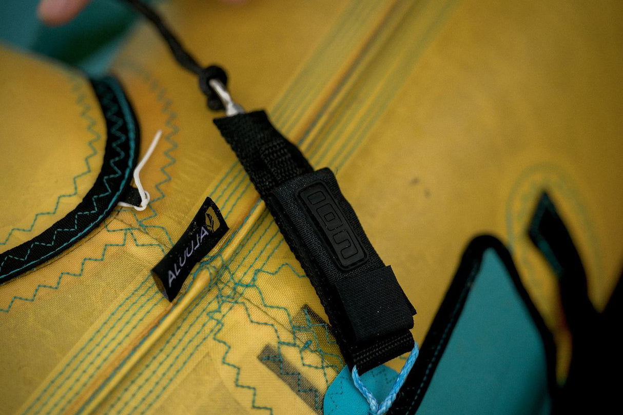 ION Wing Leash Core Extended Wrist 2024 schwarz mit Handgelenkschlaufe auf gelbem Kite, Detailansicht