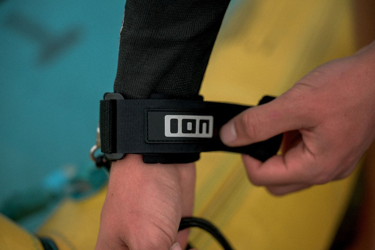 ION Wing Leash Core Extended Wrist 2024 schwarze Handgelenkschlaufe mit Logo, am Arm getragen, Detailaufnahme