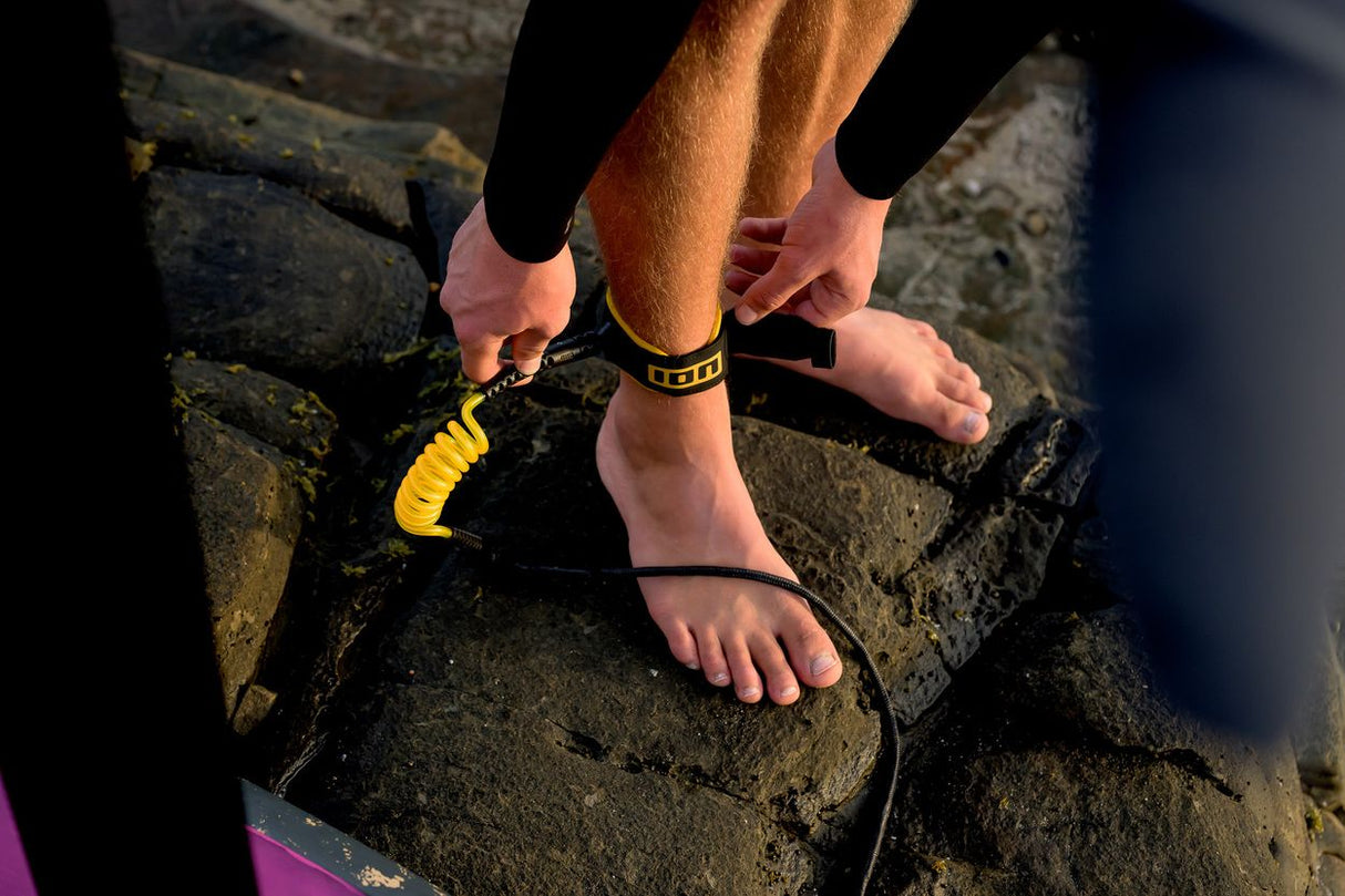 ION Wing Board Leash Core Hybrid Ankle 2026 in Gelb-Schwarz am Fuß getragen, Detailansicht der Befestigung