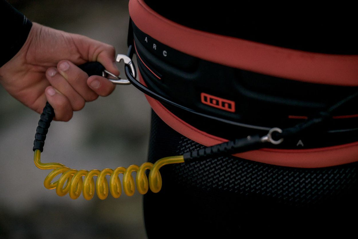 ION Wing Board Leash Core Hybrid mit Karabiner, rot-schwarz, Spiralkabel gelb, Detailansicht in Hand