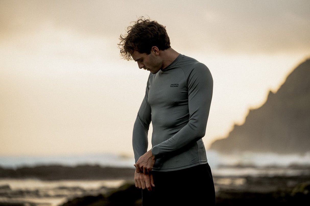 ION Rashguard LS 2026 grau, Langarm-Badeshirt aus Funktionsmaterial, getragen von Mann am Strand, Vorderansicht