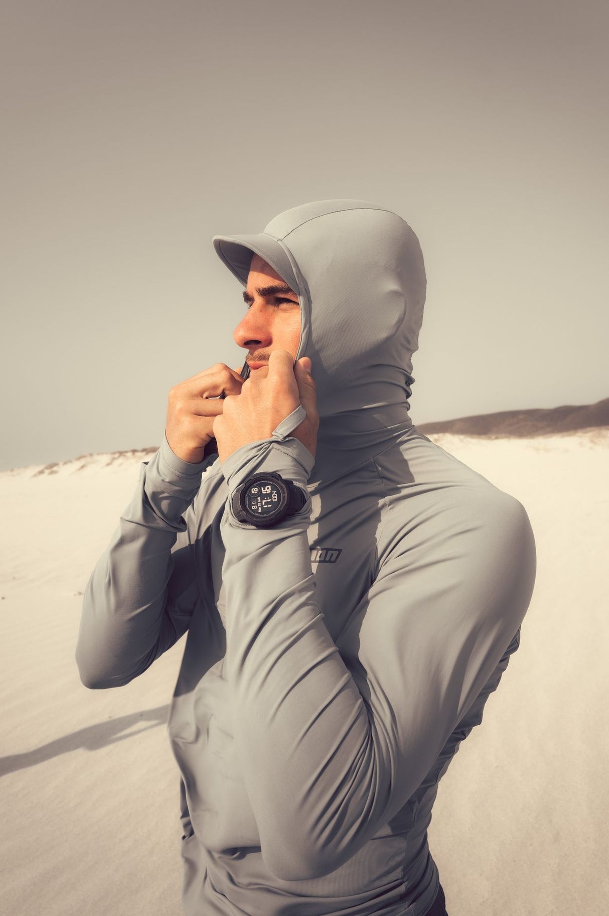 ION Rashguard Sun Pro SS26 grau mit Kapuze, Frontansicht auf Person am Strand