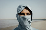 ION Storm Pro LS 2026 Kapuzen-Rashguard in Grau mit Gesichtsschutz, Frontalansicht am Strand