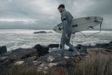 ION Seek Core 4/3 Neoprenanzug in Grau, Frontzipp, Surfer mit Surfboard am Strand