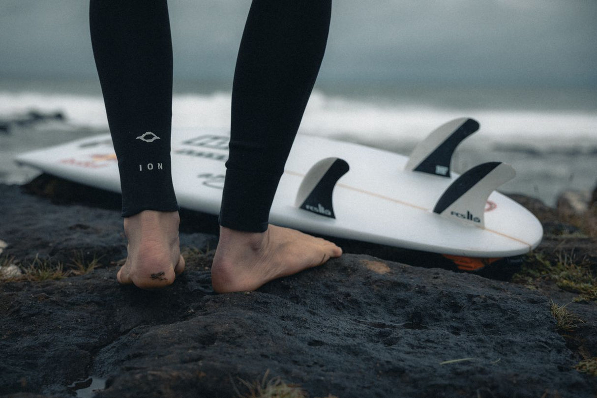 ION Seek Core 3/2 Front Zip Neoprenanzug in Schwarz, Detailansicht an den Beinen mit Surfboard