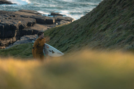 ION Seek Core 3/2 Front Zip Neoprenanzug in Braun, Surfer mit Board am Strand, Frontalansicht