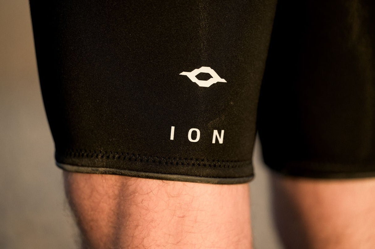 ION Seek Core 3/2 Shorty LS Frontzip Herren Neoprenanzug schwarz, Nahaufnahme Beinbereich mit ION-Logo