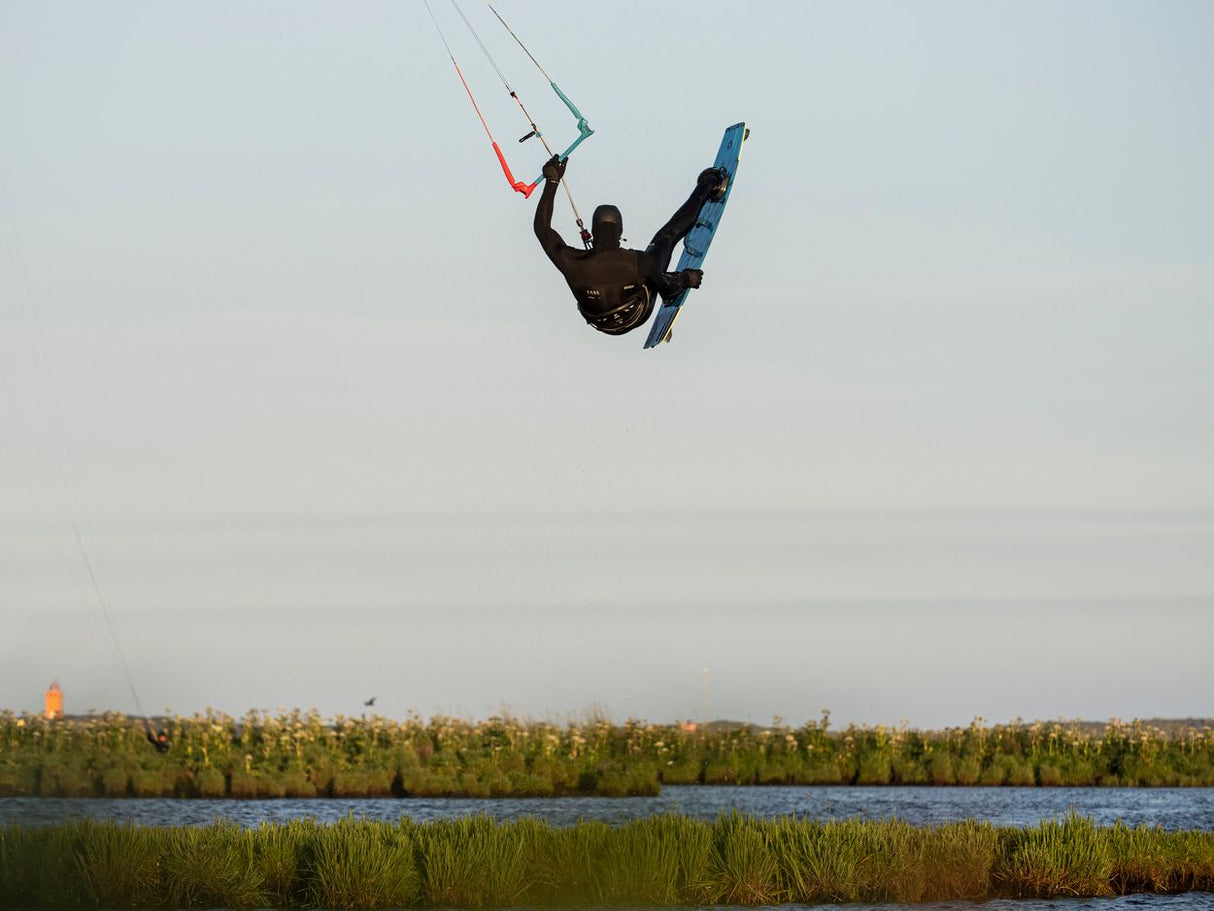 ION Riot Light 2026 Kite in Blau und Rot, Kitesurfer in Aktion über Wasser, Frontalansicht