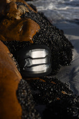 ION Riot Curv 2026 Kiteboard mit schwarzem Obermaterial und Grifffläche, Detail-Nahaufnahme der Bindung am Wasser