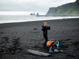 ION Neo Shelter Jacket 2024 in Schwarz, Neoprenjacke mit Reißverschluss, getragen am Strand, Frontansicht