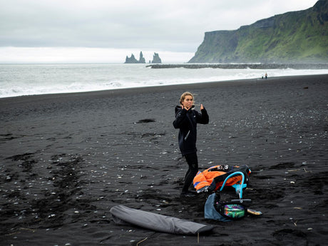 ION Neo Shelter Jacket 2024 in Schwarz, Neoprenjacke mit Reißverschluss, getragen am Strand, Frontansicht