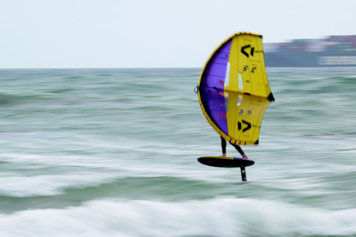 ION Hüftgurt 2026 gelb-violett, Kitesurfing-Hüftgurt in Aktion über dem Meer, Seitenansicht mit aufgespanntem Kite