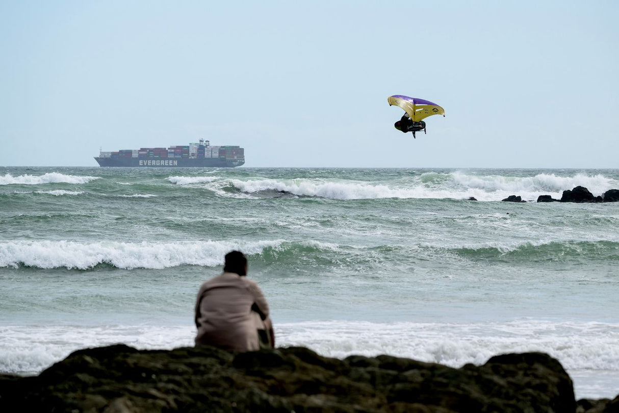ION Hüftgurt 2026 schwarz, Neopren-Kitegurt, Frontalansicht am Strand mit Kitesurfer