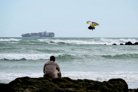 ION Hüftgurt 2026 schwarz, Neopren-Kitegurt, Frontalansicht am Strand mit Kitesurfer