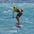 CHASE DW-R Downwind Racing Foil Board, gelb-schwarzer Neoprenanzug, Athlet in Aktion auf dem Wasser