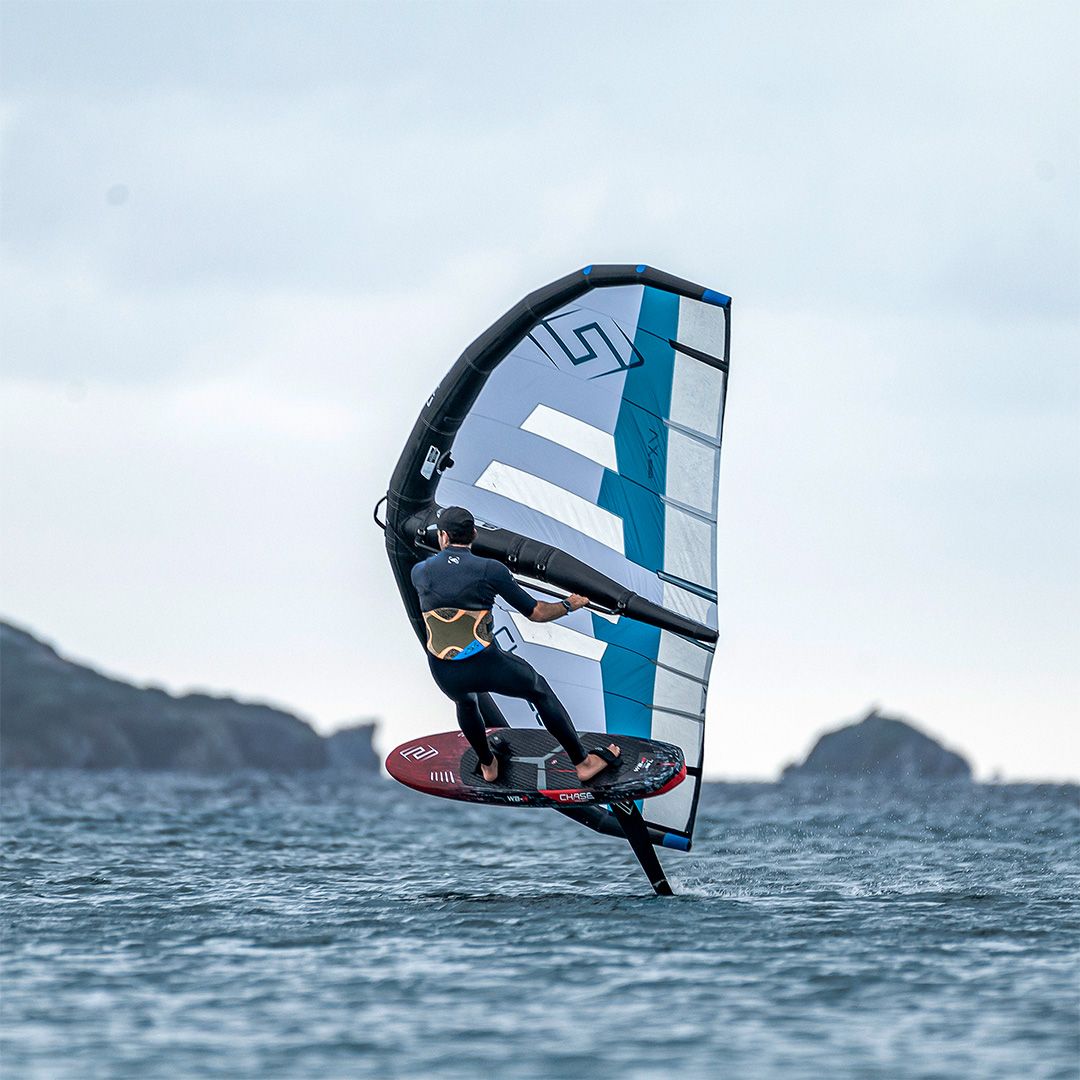 Chase WB-R Wingfoil Raceboard mit blauem Wingegel und rotem Board auf dem Wasser, Seitenansicht