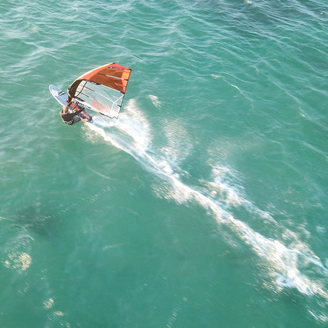 Patrik DEFI FRC Windsurfboard mit orangeweißem Segel auf türkisblauem Wasser, Draufsicht