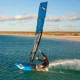 Patrik F-Ride Kiteboard blau mit Segel, Sportler in Aktion im Wasser, Strand im Hintergrund