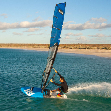 Patrik F-Ride Kiteboard blau mit Segel, Sportler in Aktion im Wasser, Strand im Hintergrund