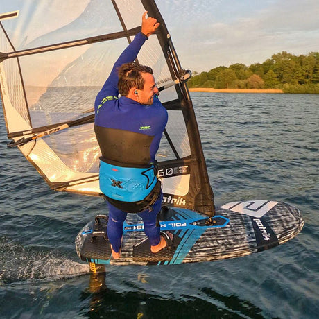Patrik Foil Ride Foilboard mit Segel, blau-schwarzes Design, Foiler in Action auf dem Wasser