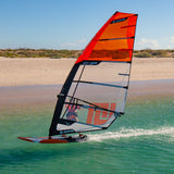 Patrik F-Race Windsurfboard mit rotem Segel im Wasser, Seitenansicht am Strand