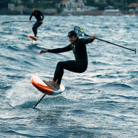 Chase DW-X Downwind SUP orange und schwarz im Einsatz auf Wellen mit Athlet in Neoprenanzug
