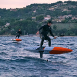 Chase DW-X Downwind SUP in Blau-Orange, Athlet beim Fahren auf Wasser mit Paddel, Flügel sichtbar