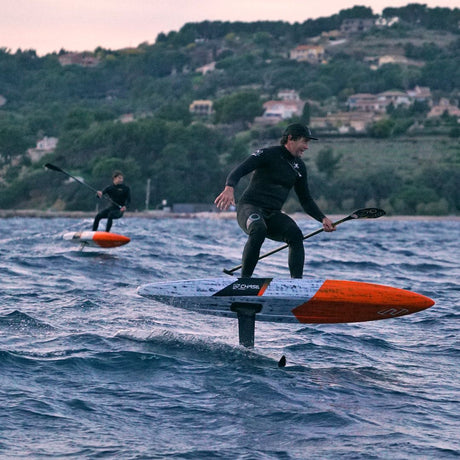 Chase DW-X Downwind SUP in Blau-Orange, Athlet beim Fahren auf Wasser mit Paddel, Flügel sichtbar