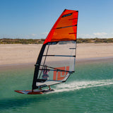 Patrik GT-3 FRC Windsurfboard rot mit Segel im Wasser, Seitenansicht am Strand